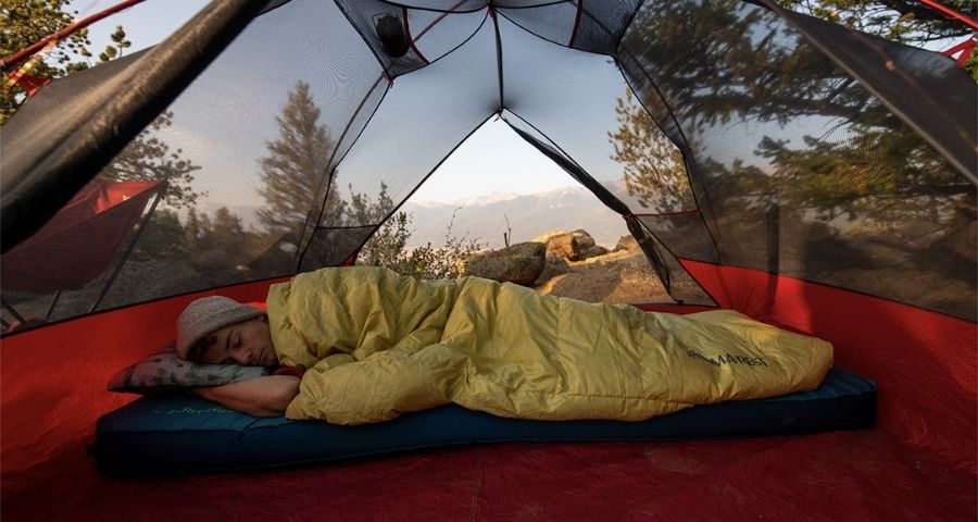 persona durmiendo en colchón de aire durante el camping
